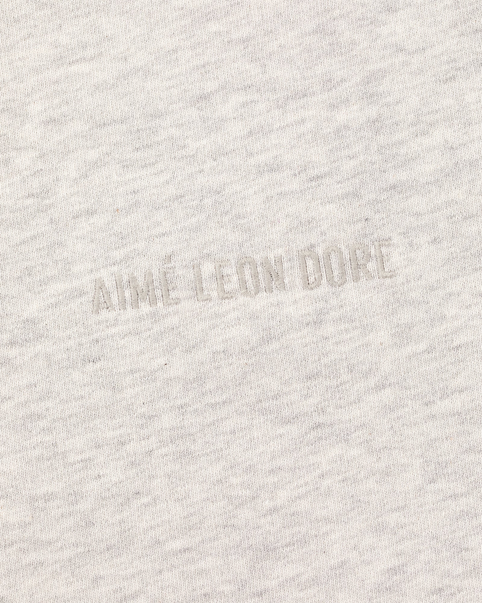Close-up of the Tonal Logo Tee's light gray fabric with a subtle, textured tonal AIME LEON DORE embroidery.