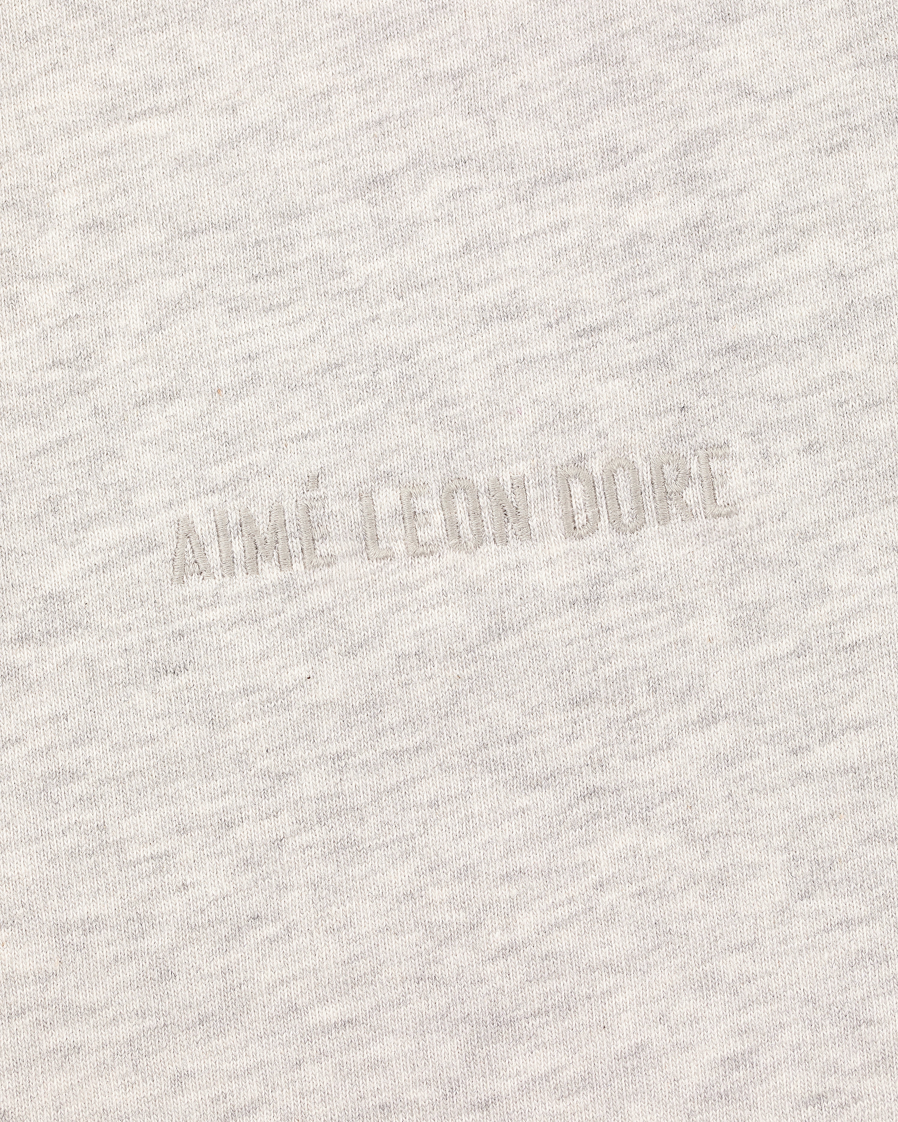 Close-up of the Tonal Logo Tee's light gray fabric with a subtle, textured tonal AIME LEON DORE embroidery.