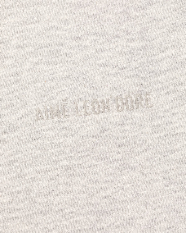 Close-up of the Tonal Logo Tee's light gray fabric with a subtle, textured tonal AIME LEON DORE embroidery.