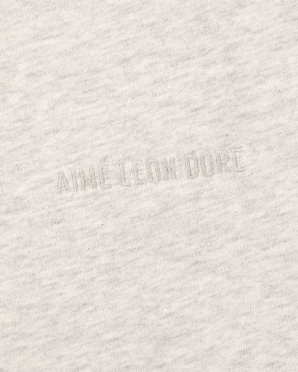 Close-up of the Long-Sleeve Tonal Logo Tee's light gray fabric with an embossed AIMÉ LEON DORE logo blending in.
