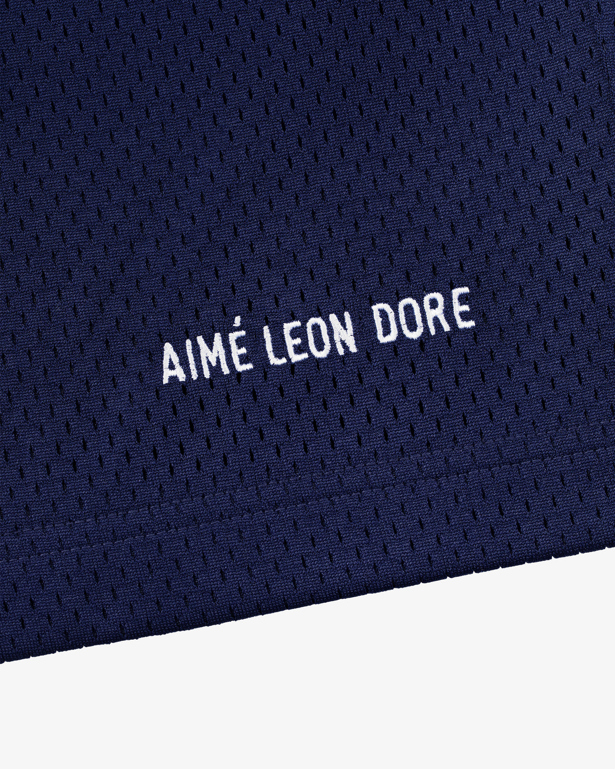 Close-up of navy blue mesh Logo Gym Short with AIMÉ LEON DORE embroidered in white capital letters.