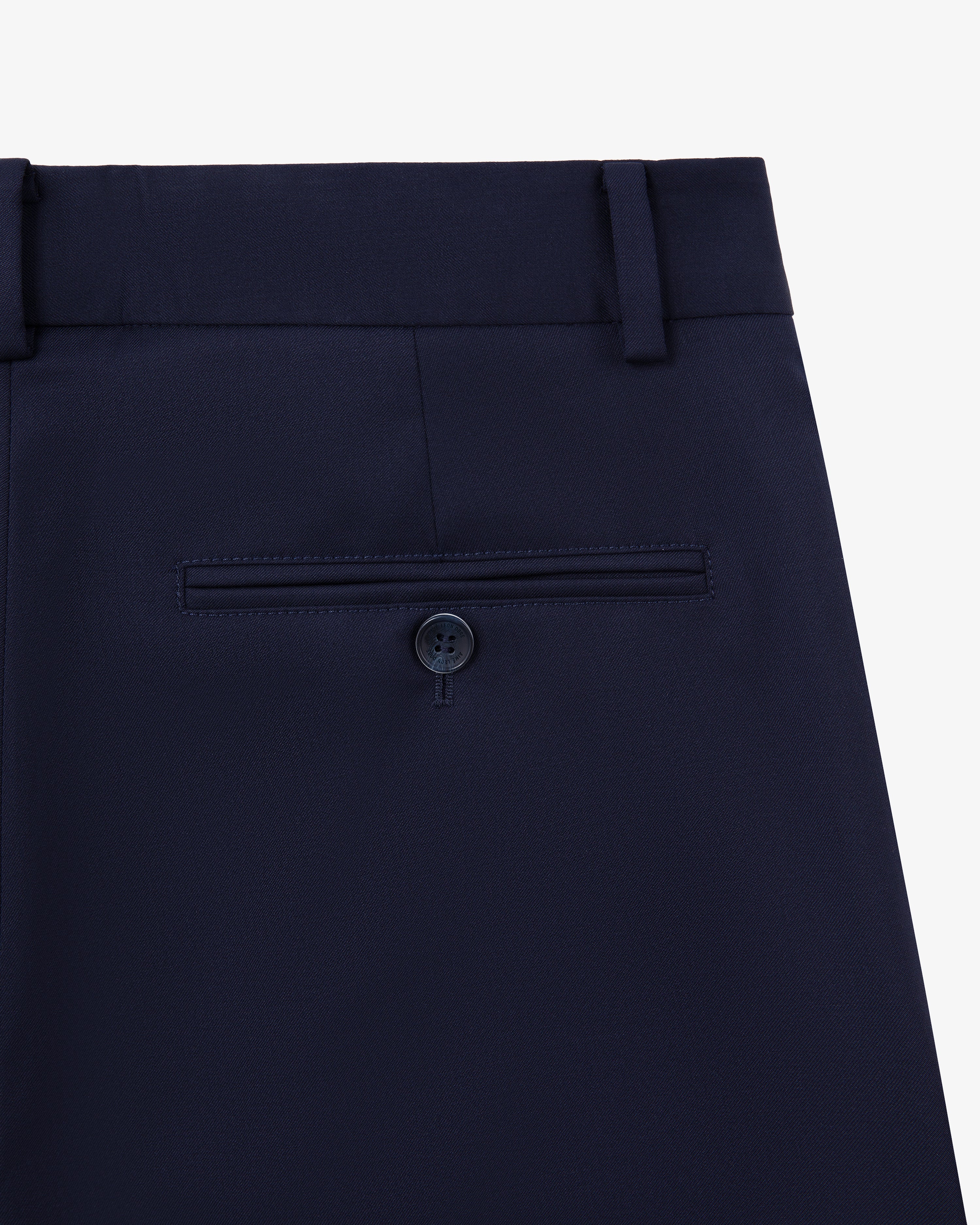 Close-up of Single-Pleated Gabardine Trouser in navy with back pocket, button, and belt loops on white background.