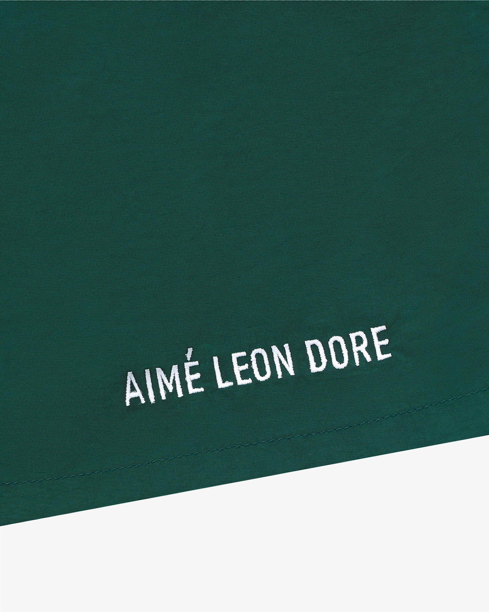 Green Core Nylon Short with white AIMÉ LEON DORE embroidery in a minimalist style near the bottom edge.