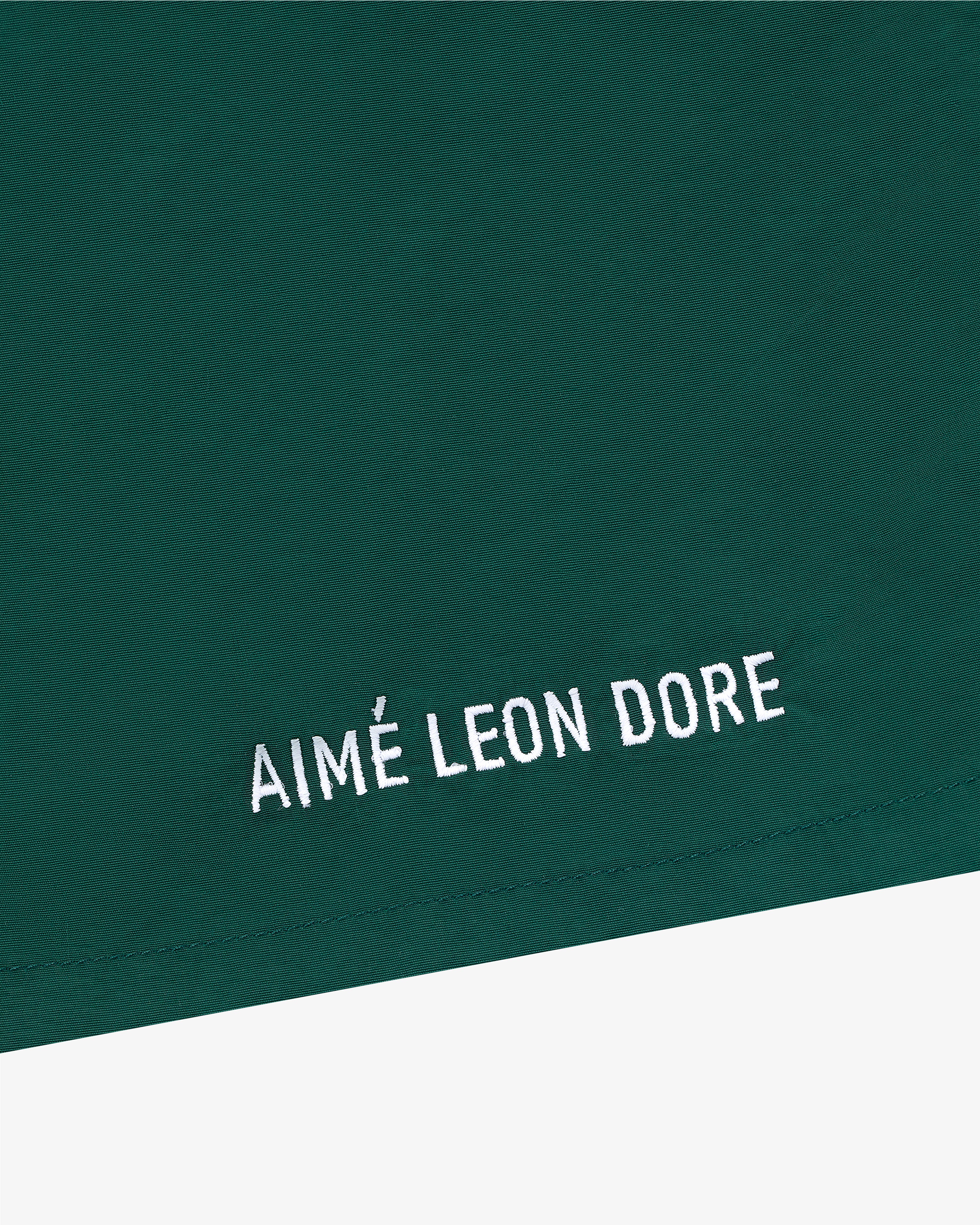 Green Core Nylon Short with white AIMÉ LEON DORE embroidery in a minimalist style near the bottom edge.