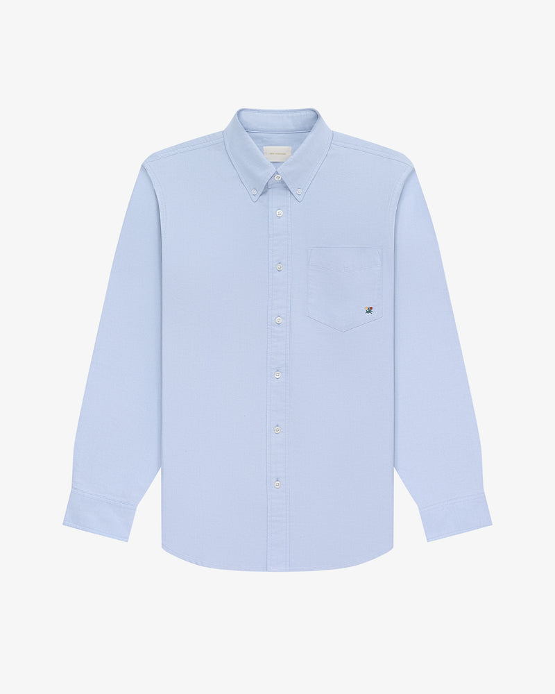Crest Oxford Shirt in light blue, long sleeves, button-up with chest pocket, on a white background.