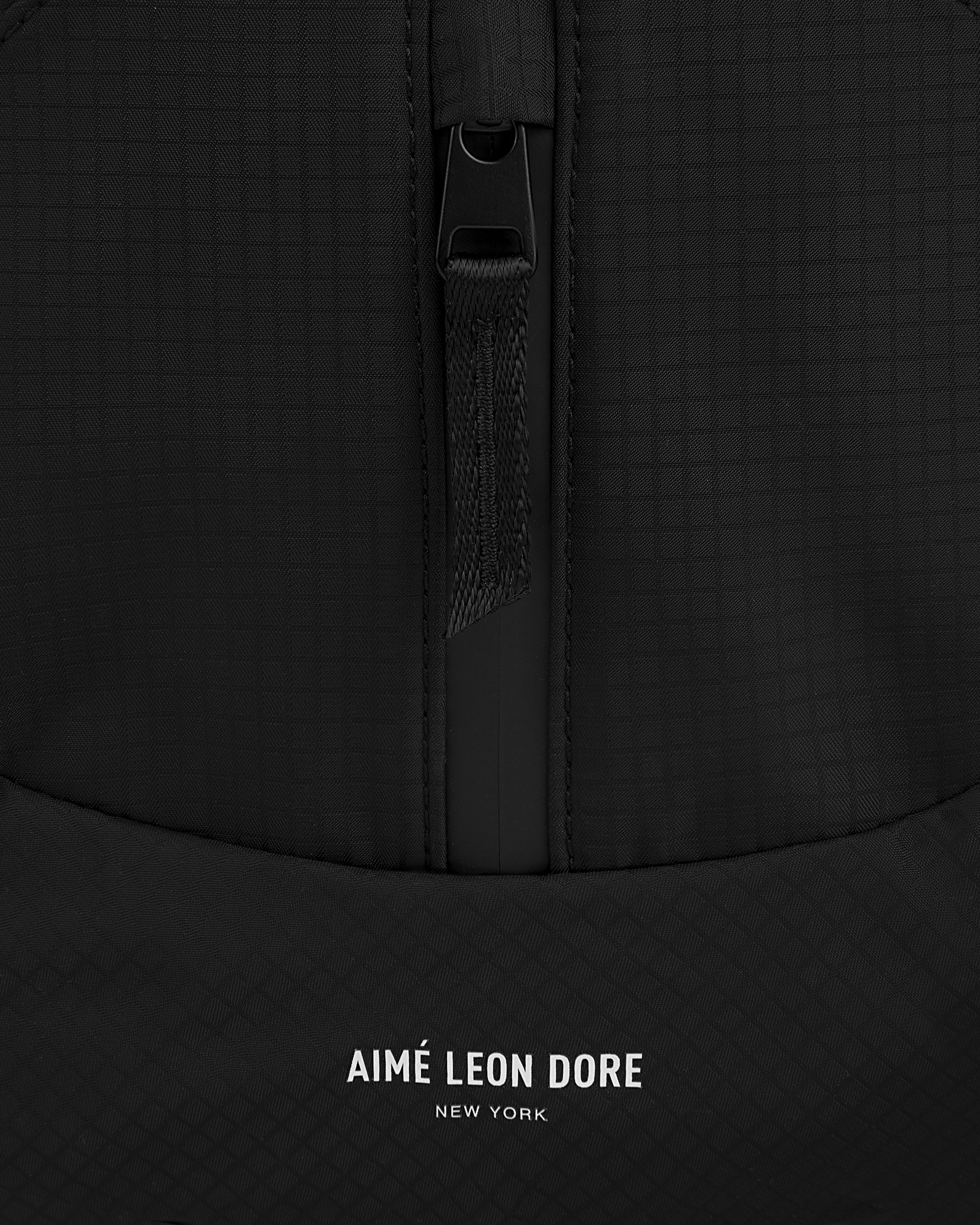 Close-up of the black Nylon Messenger Bag with a zipper and AIMÉ LEON DORE NEW YORK printed in white.