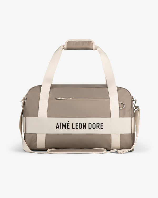 Nylon Duffle Bag in beige with white straps and "AIMÉ LEON DORE" on front, shown on a white background.