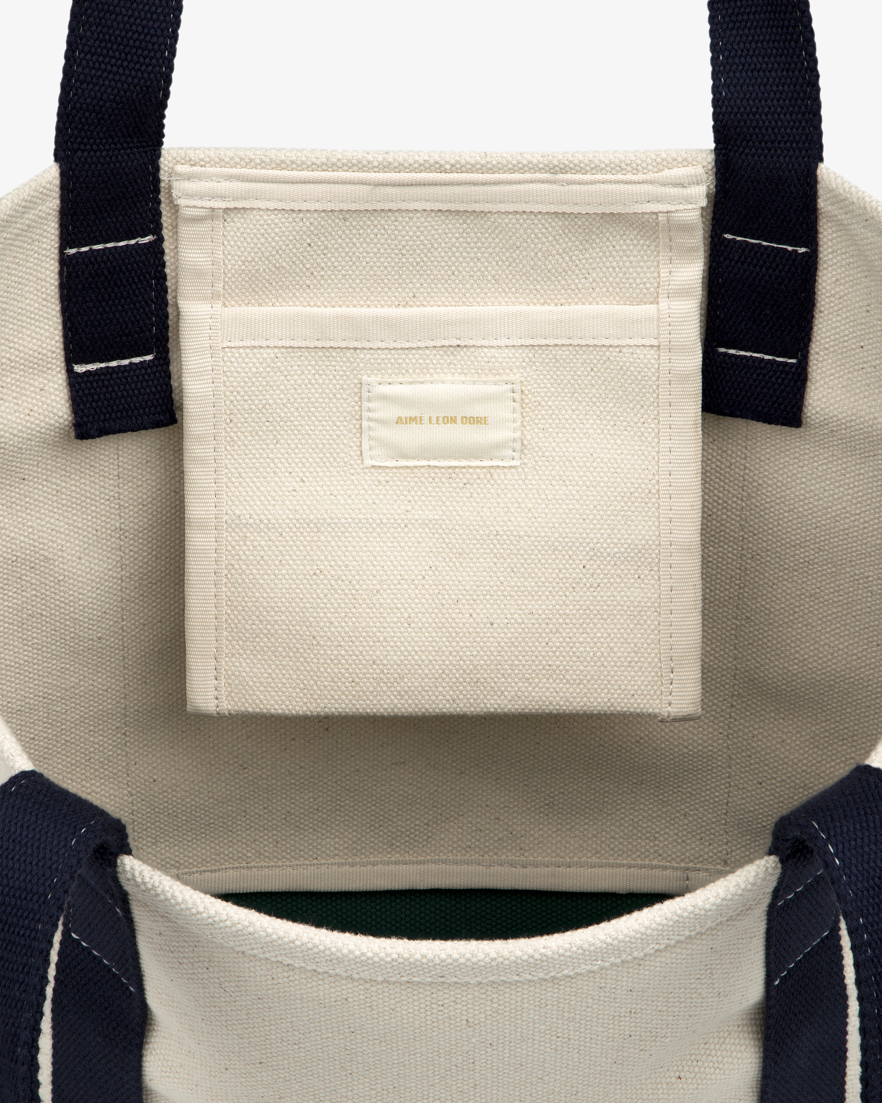 Small Crest Contrast Tote Bag with navy handles, visible white stitching, and a small interior pocket.