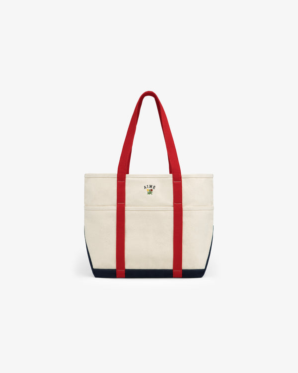 Large Crest Contrast Tote Bag with red handles, navy trim, and small floral ALME logo embroidered on the front.