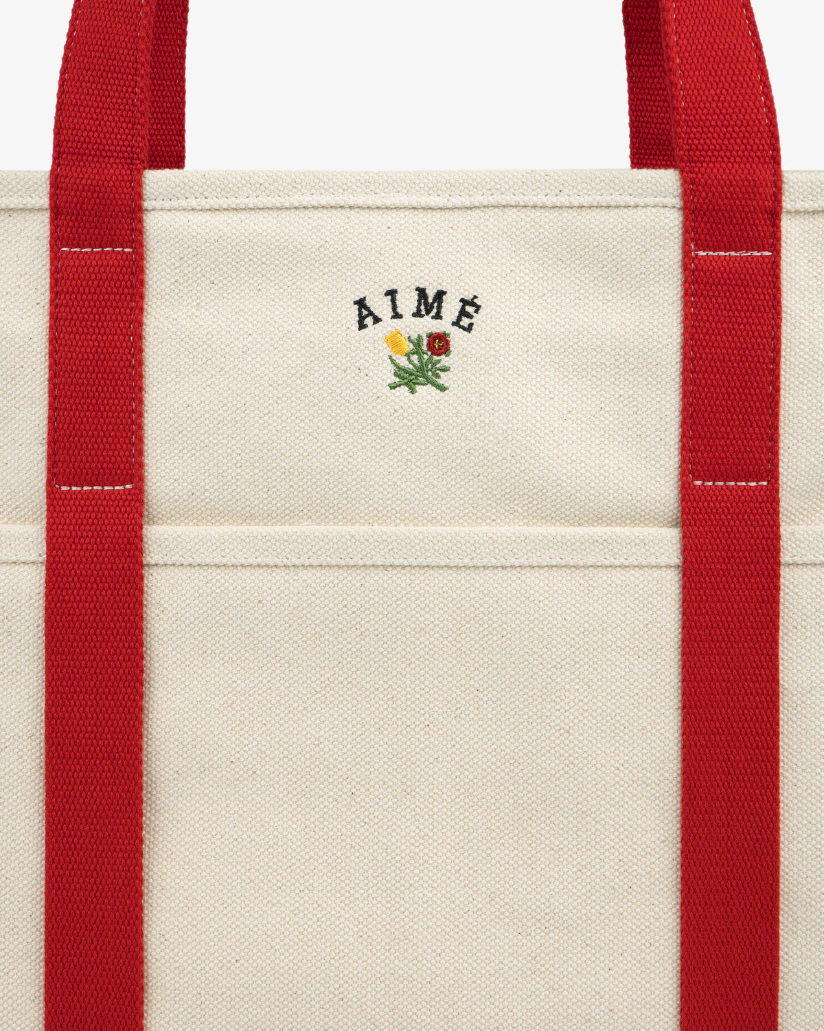 Small Crest Contrast Tote Bag in beige canvas with red straps, AIMÉ text, and a yellow-red embroidered flower.