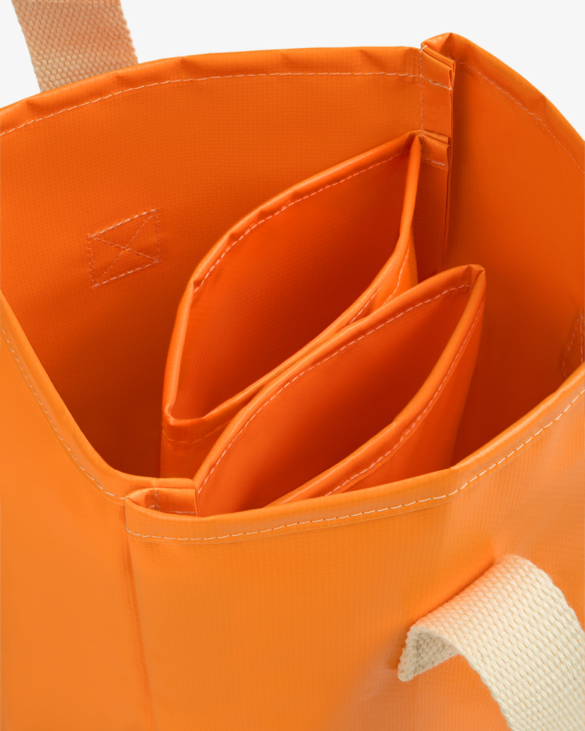 Close-up of the Marina Bottle Tote, an orange bag with beige handles and two inner pockets.
