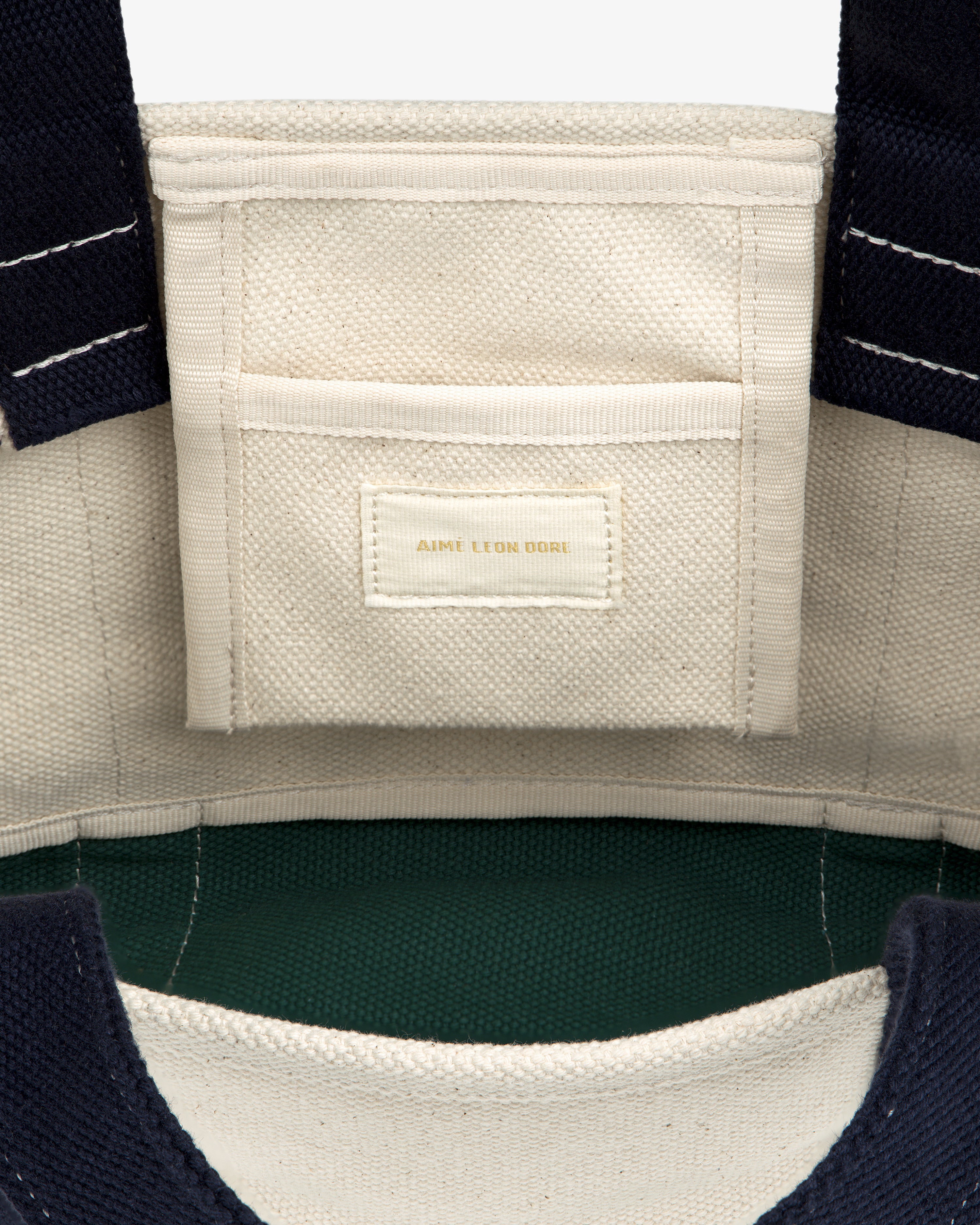 Interior of the Mini Crest Contrast Tote Bag with a small pocket and gold-stitched AIME LEON DORE label.
