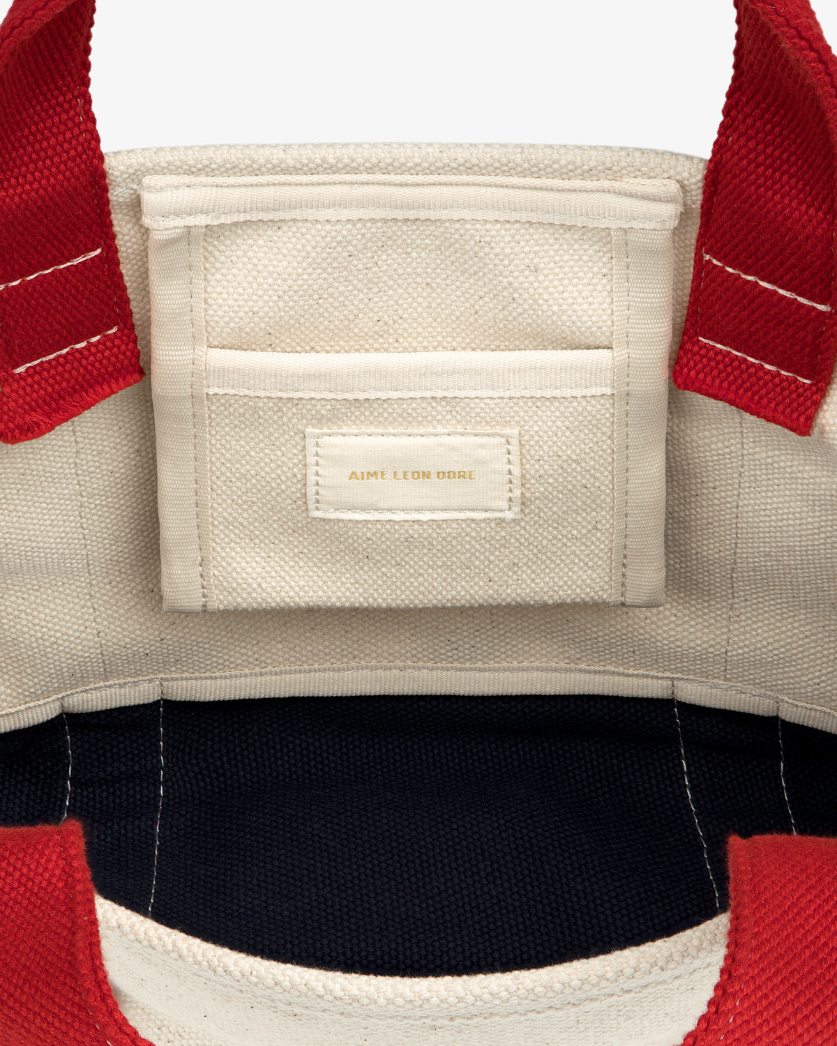 Mini Crest Contrast Tote Bag: cream canvas, red handles, interior pocket with Aime Leon Dore gold label.