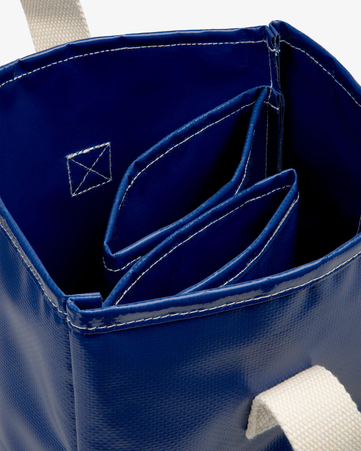 Close-up of the Marina Bottle Tote in blue with white straps and two inner pockets with white stitching.