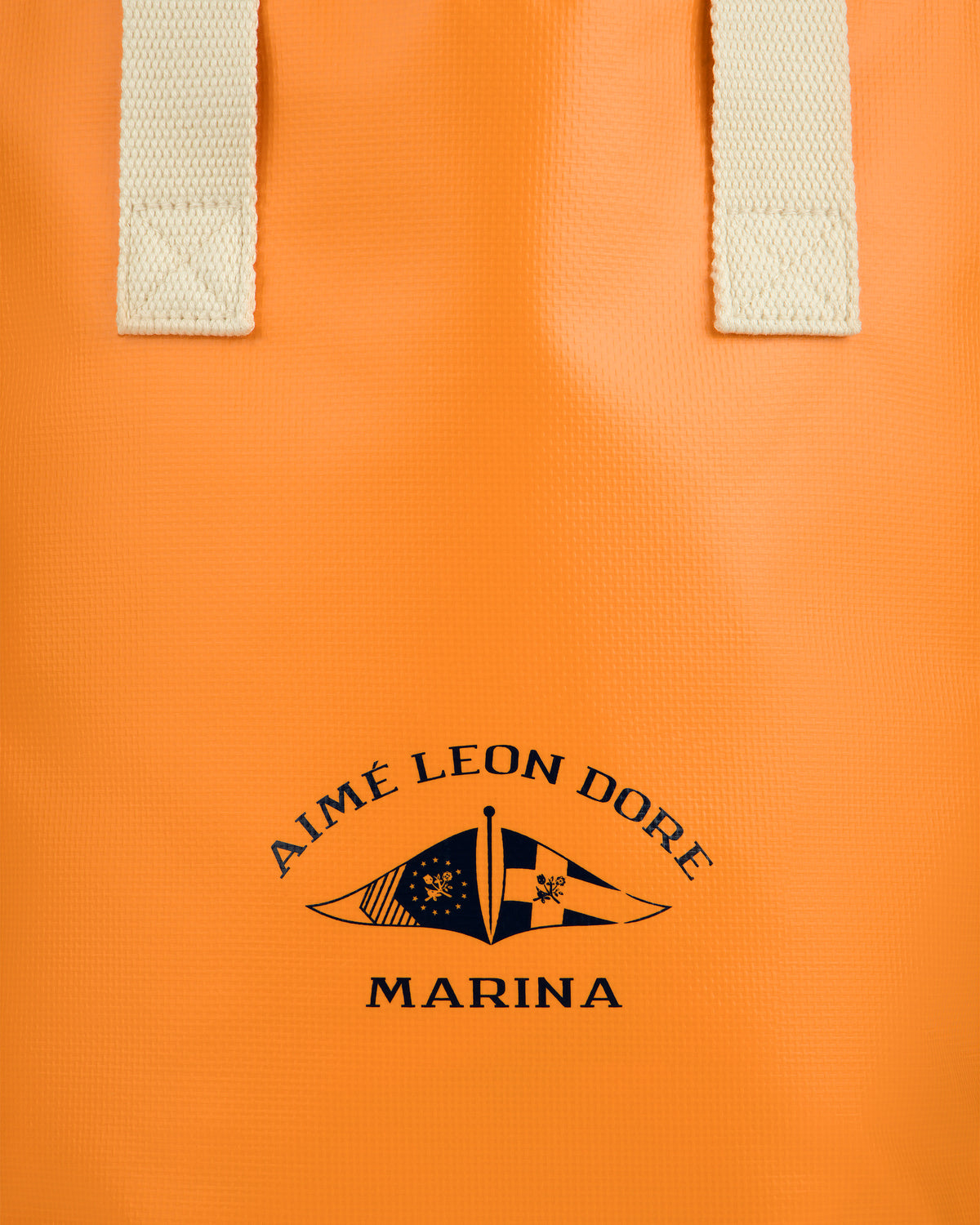 Marina Bottle Tote: Orange bag with cream handles, AIMÉ LEON DORE MARINA and two black nautical flags printed.