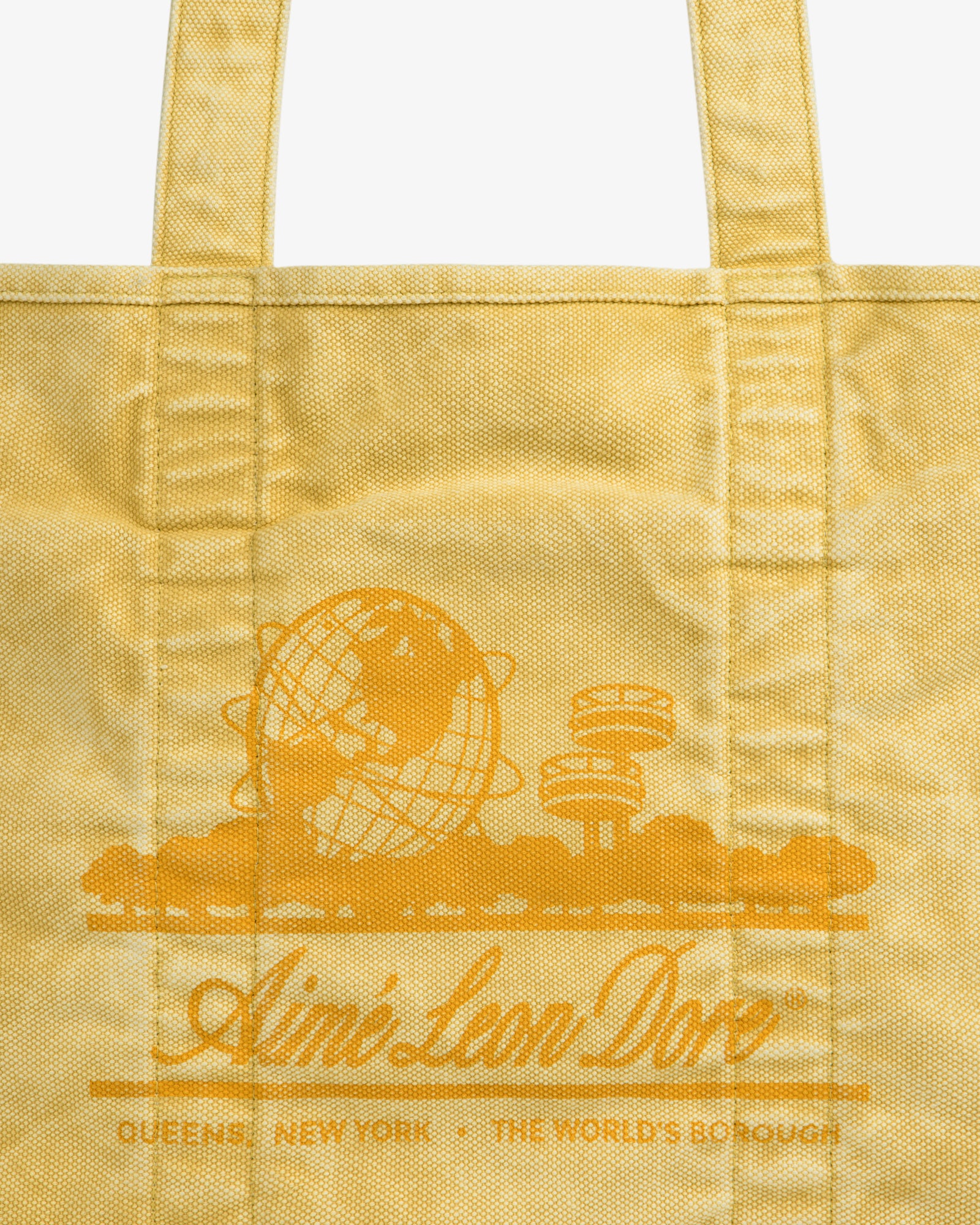 Sun Faded Large Unisphere Tote Bag: yellow with orange line art and “Ain’t Love Dope” text; Queens, New York below.