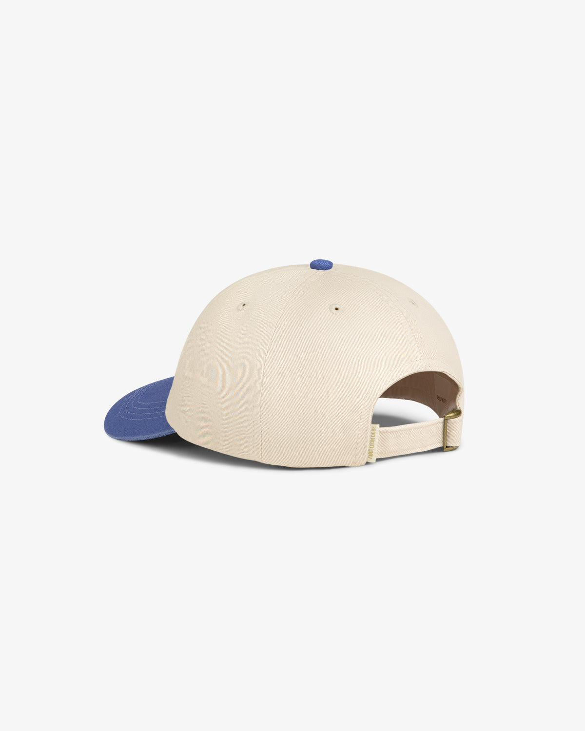The Washed Chino Hat is a beige baseball cap with a blue brim, blue button, and adjustable strap shown from the back.