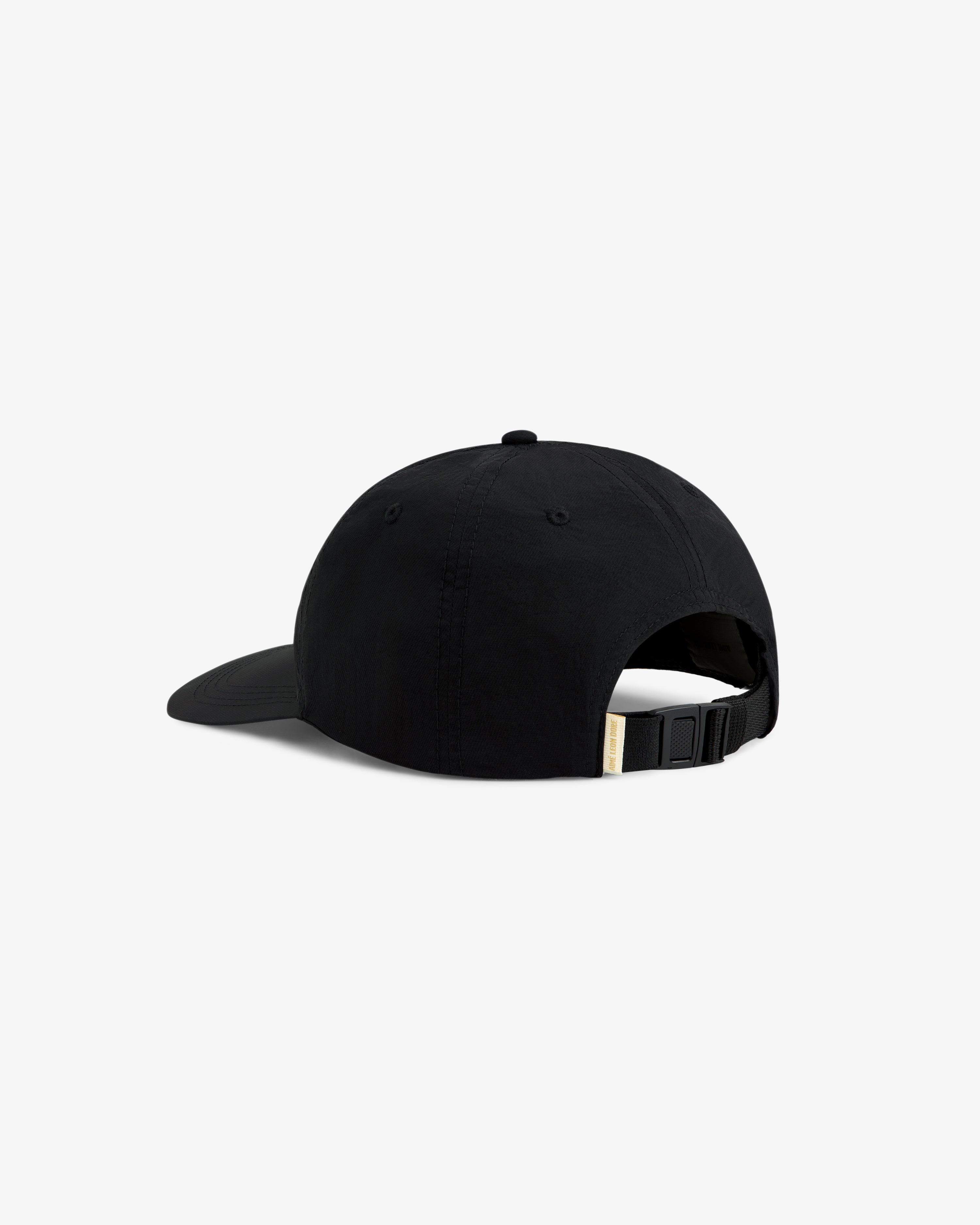 The Krylon Label Hat is a black cap with a curved brim, shown from the back, and features an adjustable strap.