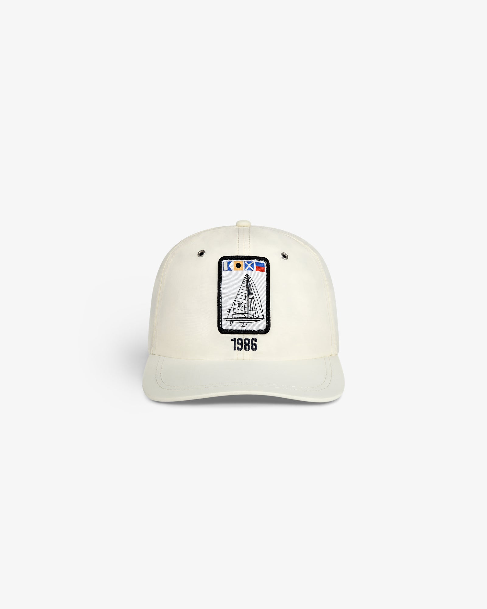 The Nylon Deck Hat is a white baseball cap with an embroidered sailboat patch and "1986" printed below it on the front.