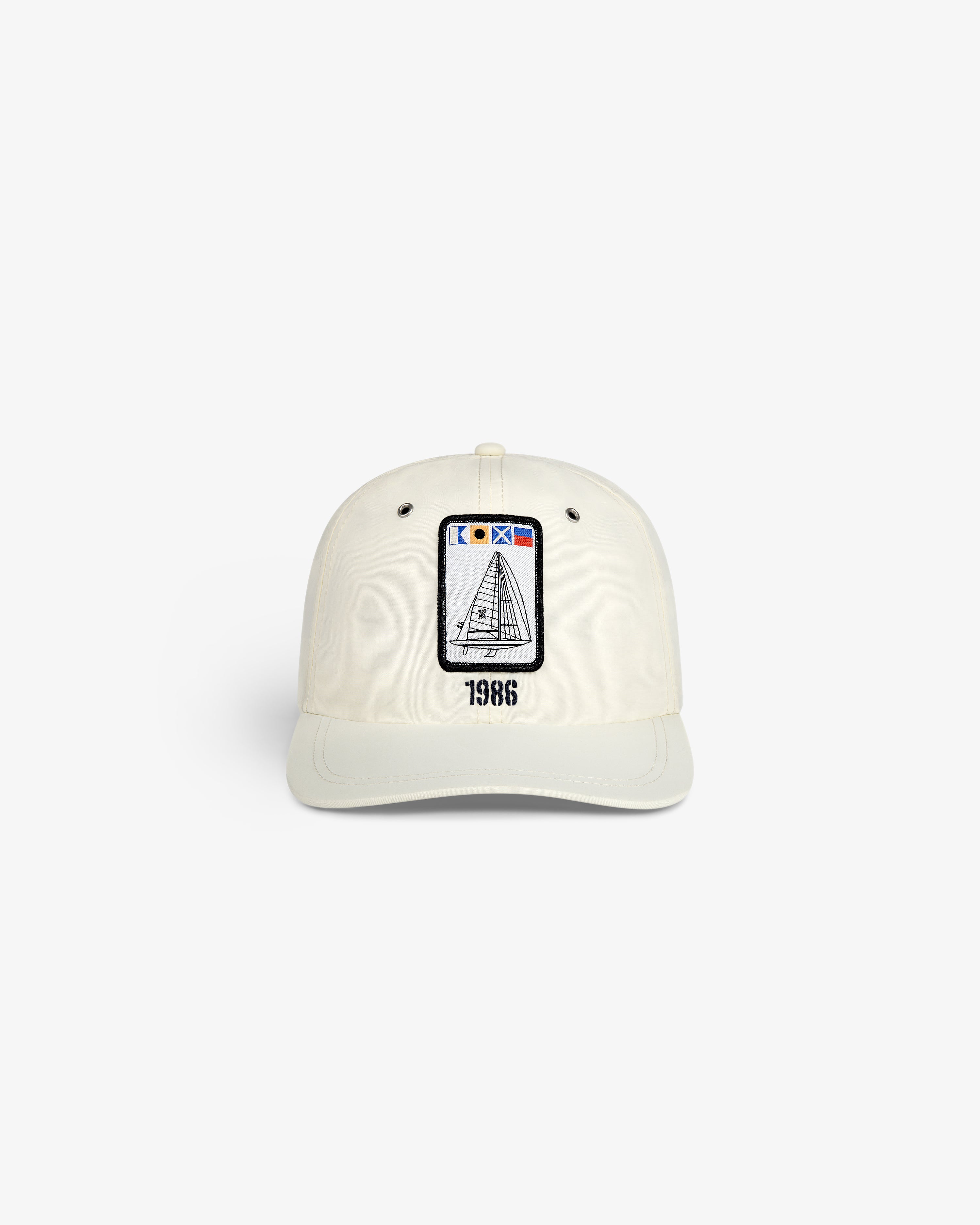 The Nylon Deck Hat is a white baseball cap with an embroidered sailboat patch and "1986" printed below it on the front.