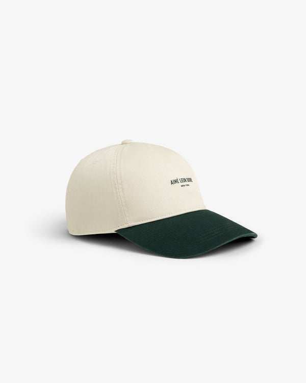 Micro Logo Hat in beige with a dark green brim and small front text, displayed on a white background.