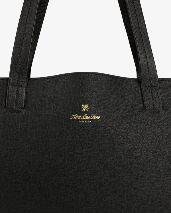 Close-up of a Full Grain Leather Tote Bag in black with Aimé Leon Dore New York and gold crest logo on the front.
