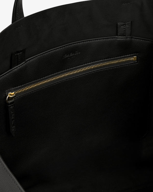 Close-up of the Full Grain Leather Tote Bag's black leather interior with gold zipper pocket and suede lining.