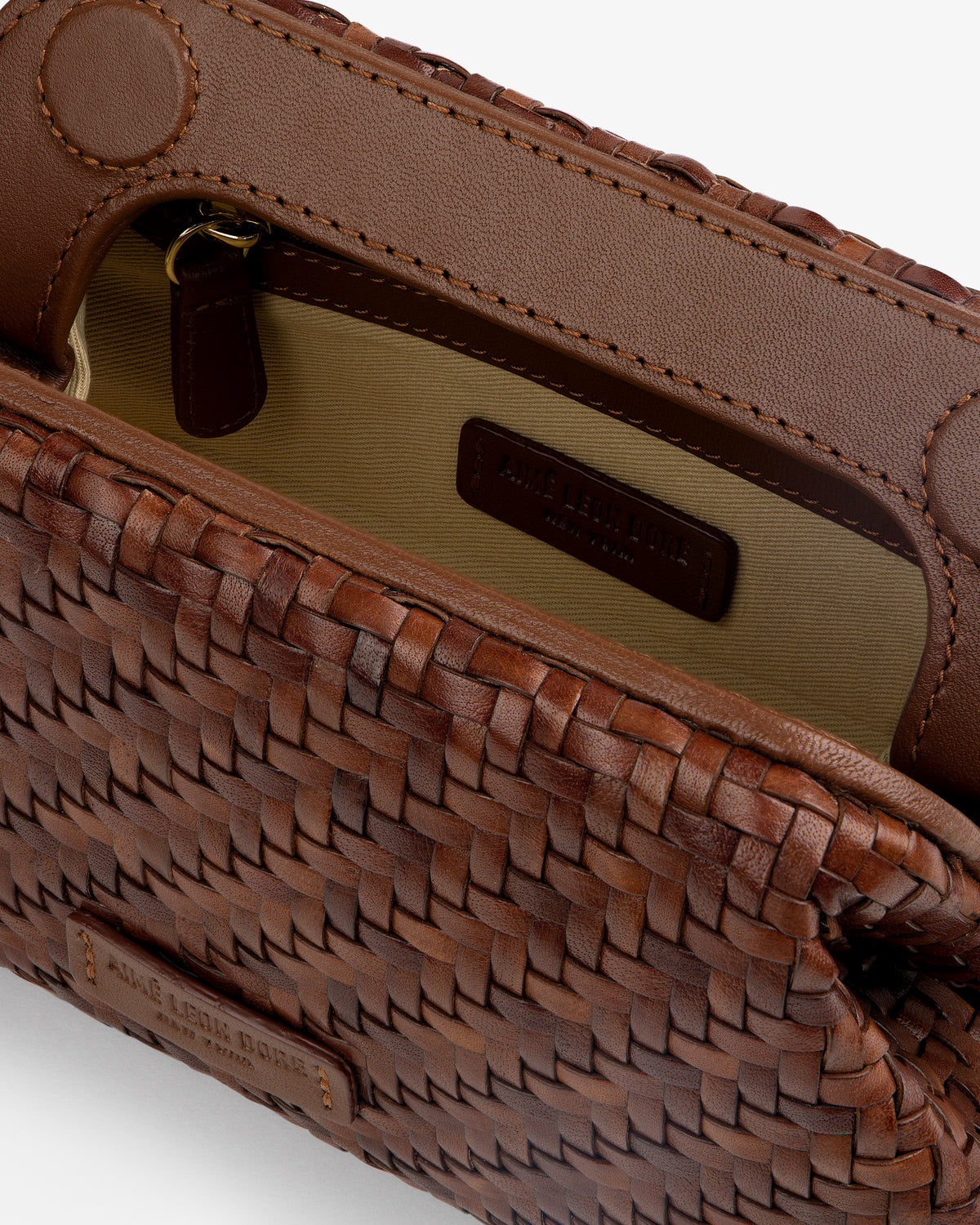 Close-up of the Woven Leather Shoulder Bag, open to show its beige interior and zippered pocket.