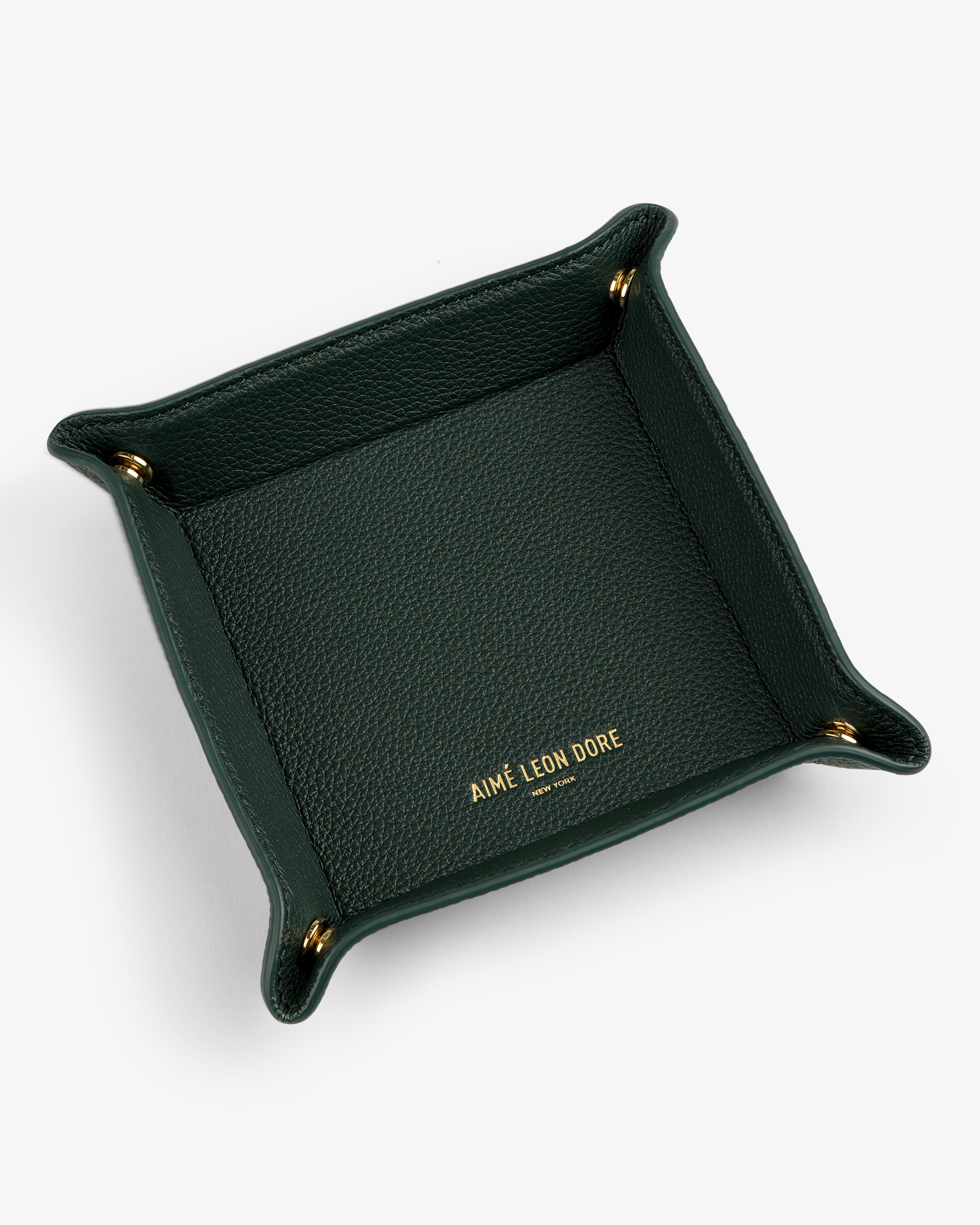 A dark green Leather Catchall with gold corner snaps and AIMÉ LEON DORE embossed in gold inside.