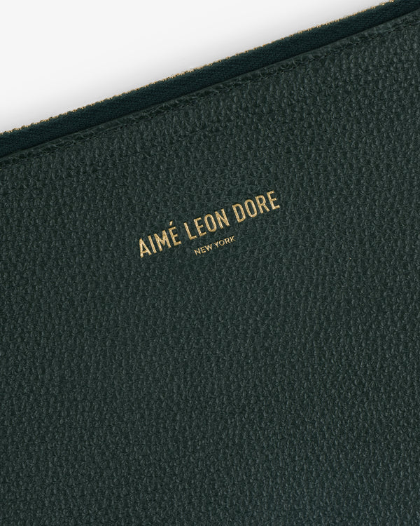 Close-up of the Large Leather Pouch’s textured dark green surface with Aimé Leon Dore New York in gold lettering.