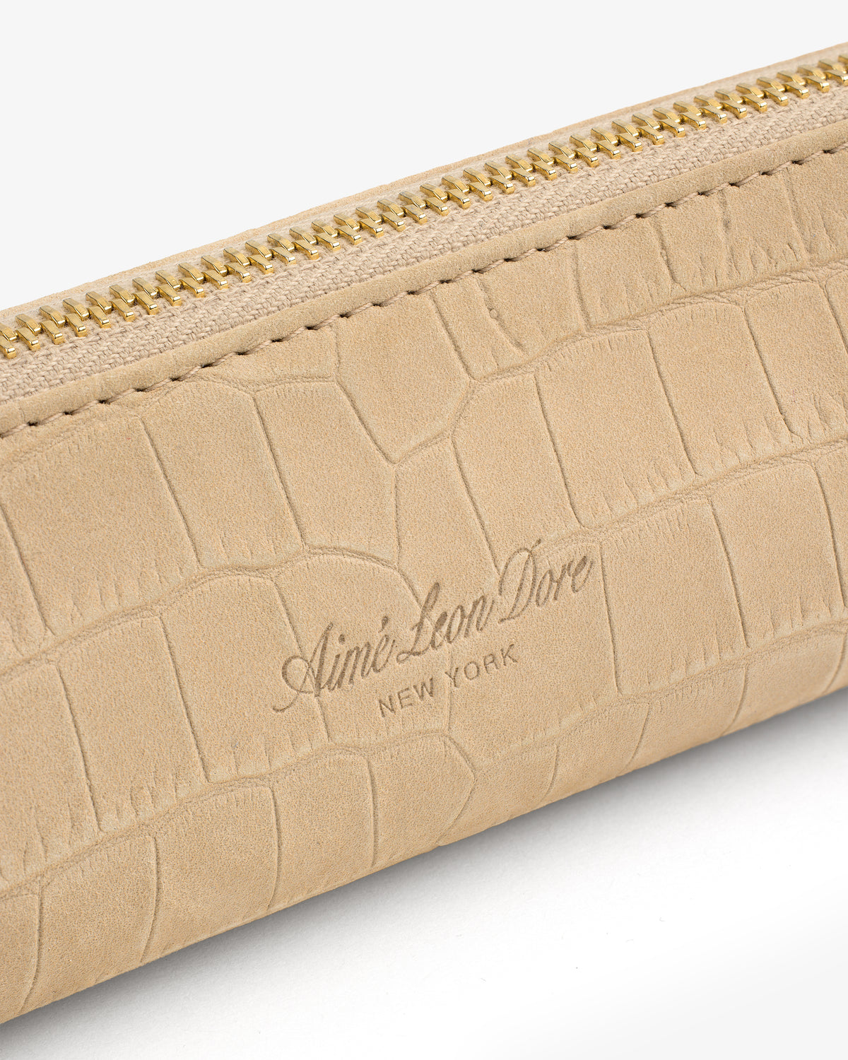 Close-up of the Croc-Embossed Nubuck Pencil Case with gold zipper and Aimé Leon Dore New York embossed on beige leather.
