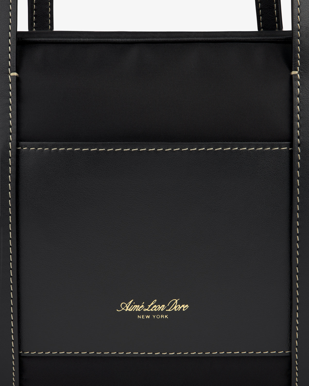 Close-up of a black Mini Duffle Shoulder Bag with white stitching and gold Aimé Leon Dore New York logo on the front pocket.