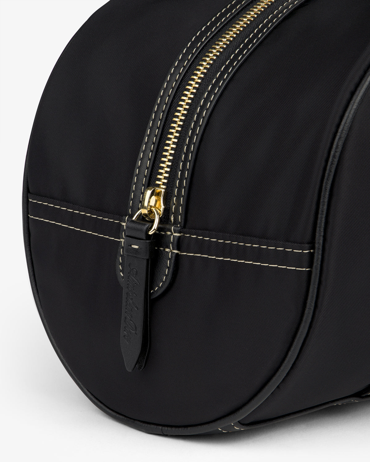 Close-up of the Mini Duffle Shoulder Bag in black with white stitching, gold zipper, and leather pull.