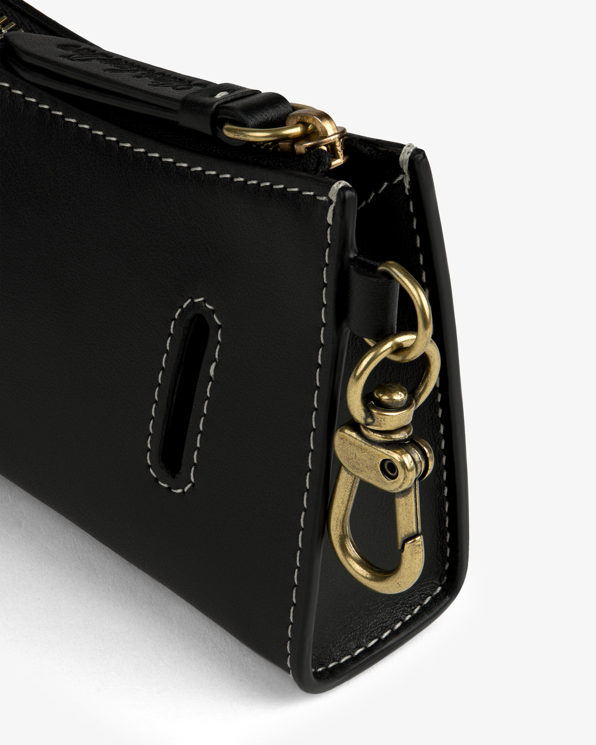 Close-up of the Convertible Leather Belt Bag's black leather corner with white stitching and a gold swivel clasp.