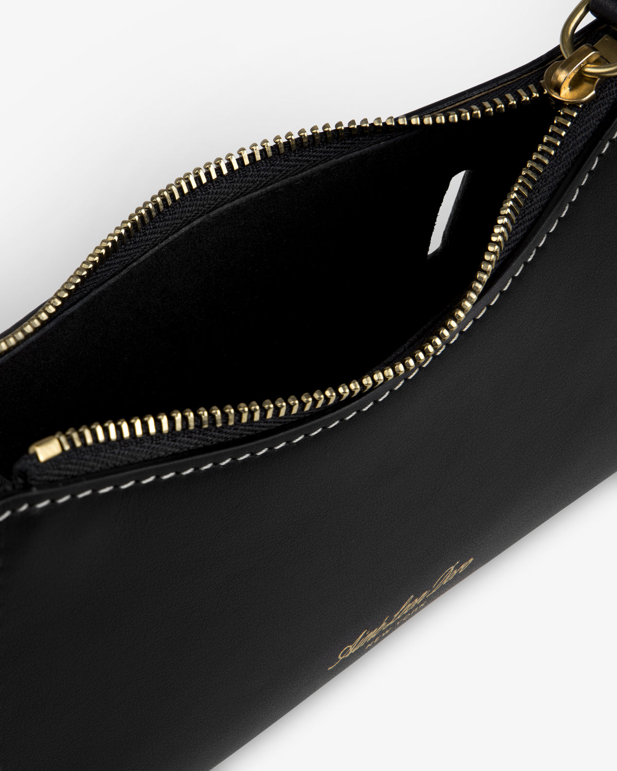 Close-up of an open Convertible Leather Belt Bag in black leather with a gold zipper and white stitching.