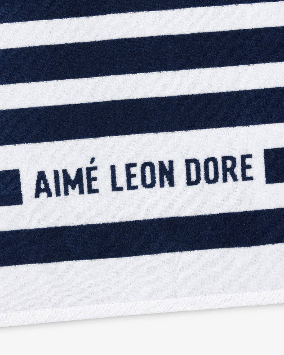 Striped Beach Towel in navy and white with AIMÉ LEON DORE text printed in navy on a white stripe.