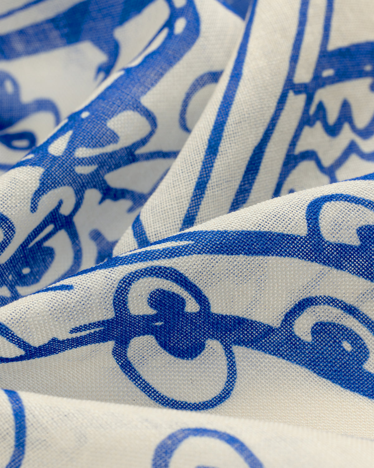 Close-up of Fassianos Wool Silk Bandana featuring white fabric with abstract blue patterns and textured folds.