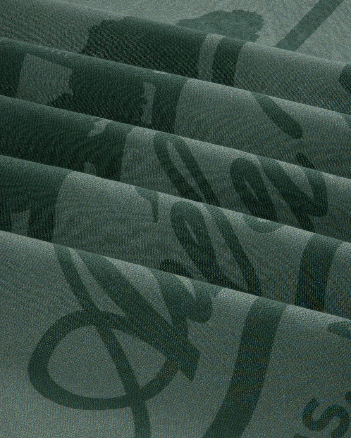 Sun Faded Unisphere Bandana in dark green with shiny cursive script, folded in neat pleats.