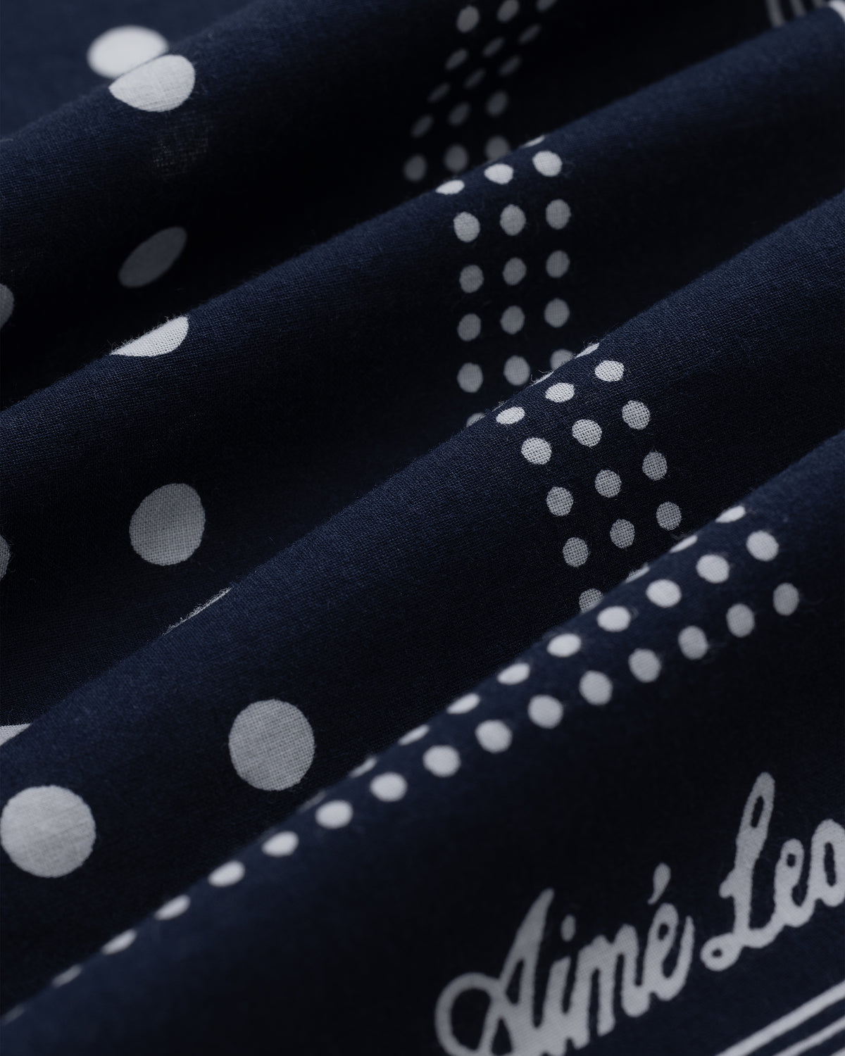 Navy blue Polka Dot Bandana with white polka dots and partial script text reading “Aimé Leo.”.