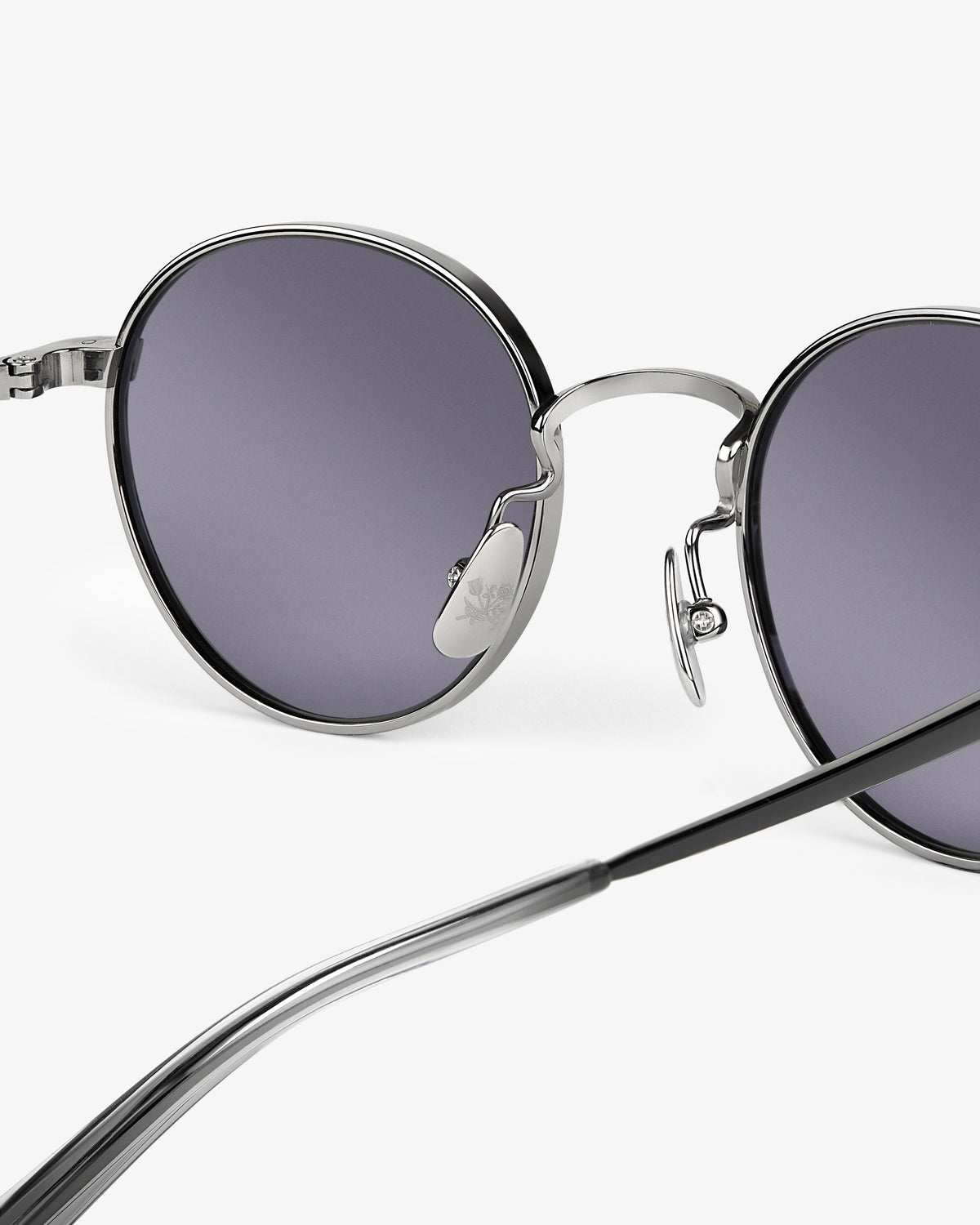 Close-up of Giórgios Sunglasses: round, silver frames, dark lenses, black temples, on a white background.
