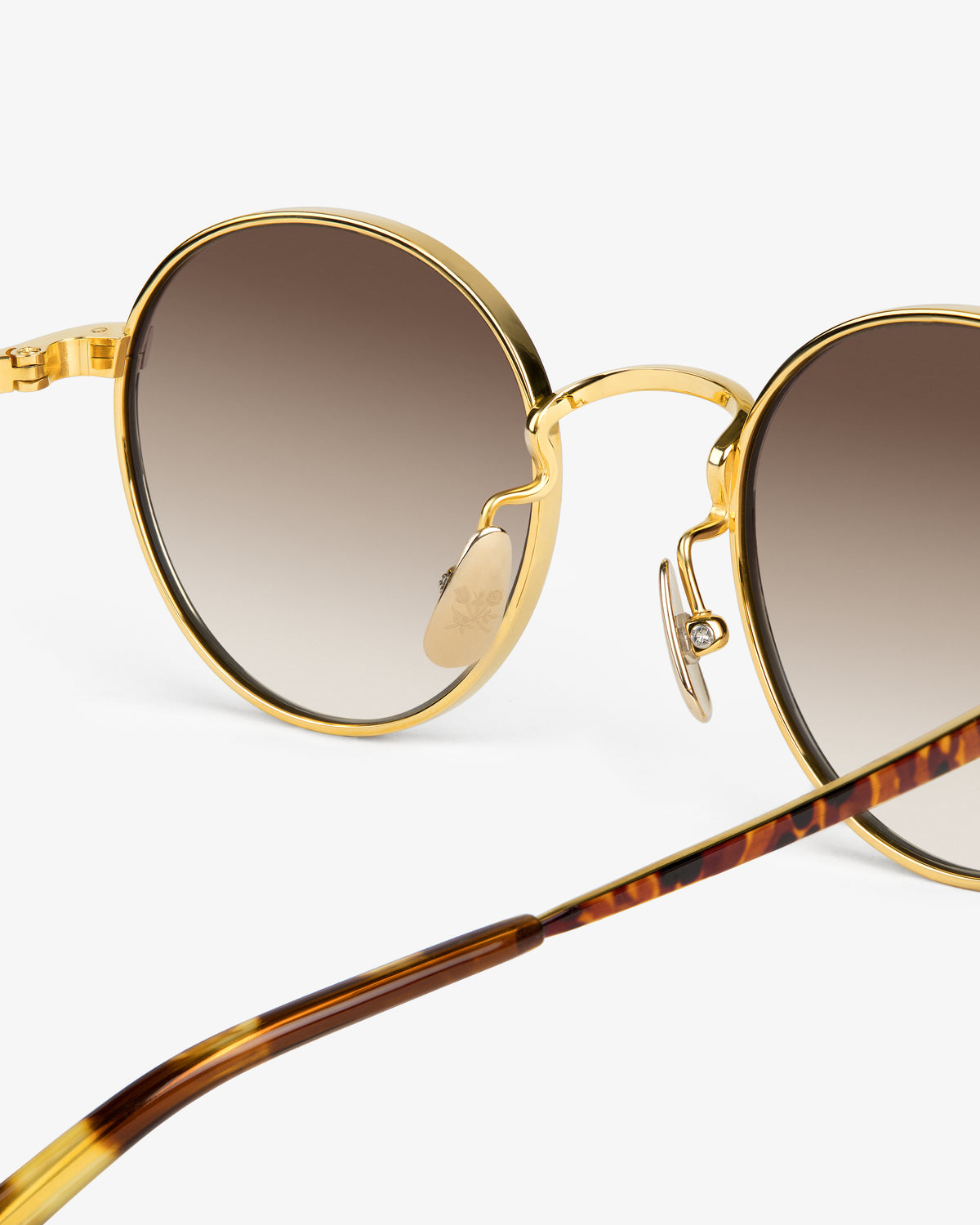 Close-up of Giórgios Sunglasses: gold-rimmed, round frames with gradient lenses and tortoiseshell arms on white.