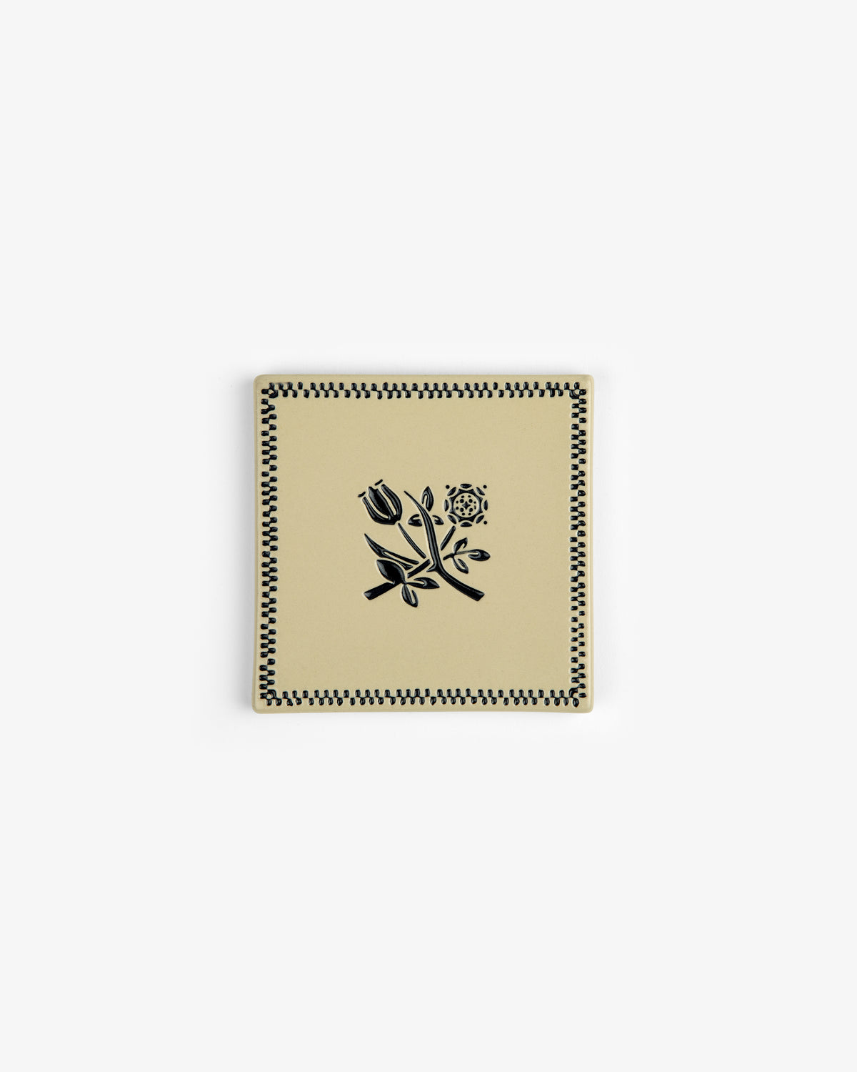 The Crest Coaster (Set of 4) features square beige ceramic pieces with black floral and checkered designs.