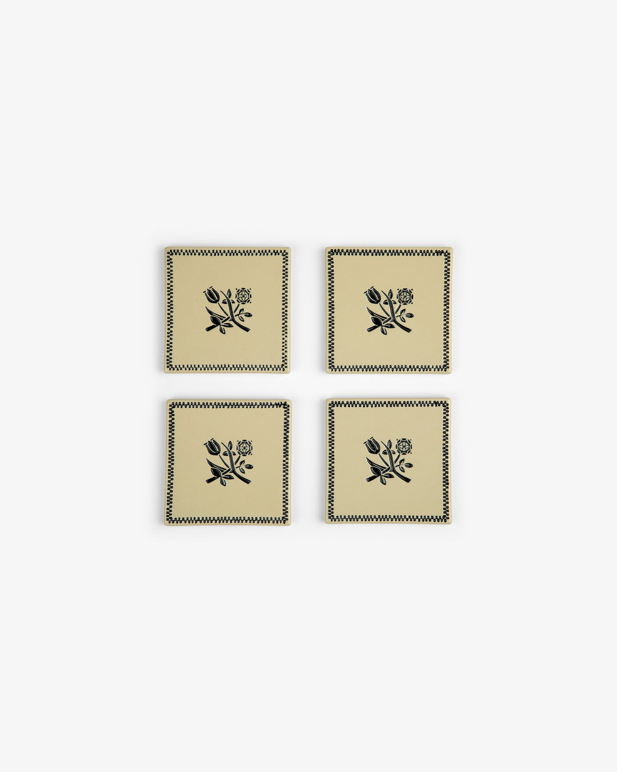 The Crest Coaster Set (4 pcs) features beige coasters with black floral designs and zigzag borders, arranged in a grid.