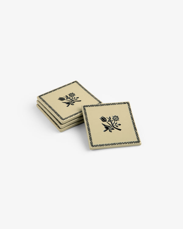 Set of 4 Crest Coasters: beige squares with black floral designs and patterned borders, stacked on a white background.