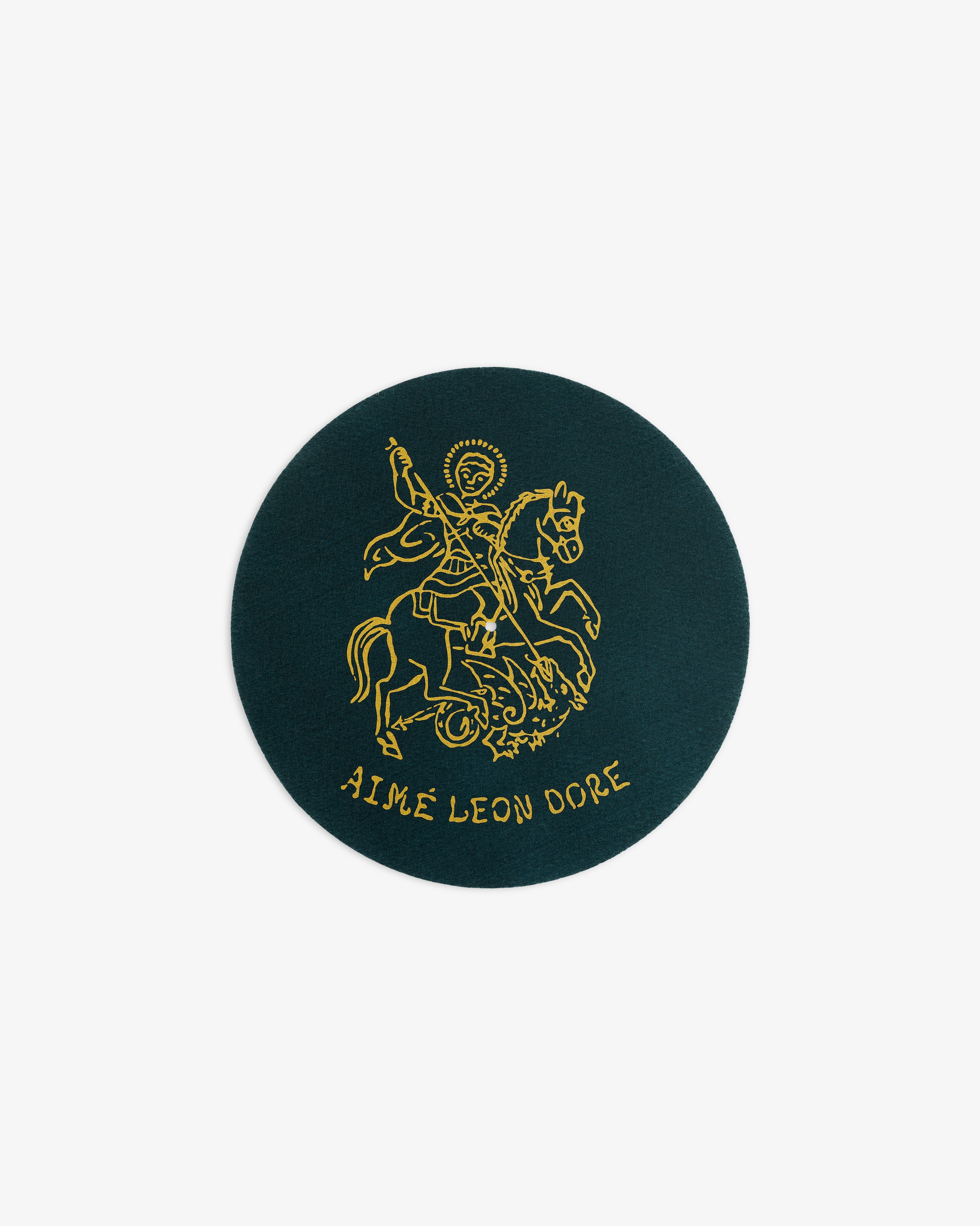 Round green Graphic Slip Mat featuring a gold knight on horseback and AIMÉ LEON DORE text below.