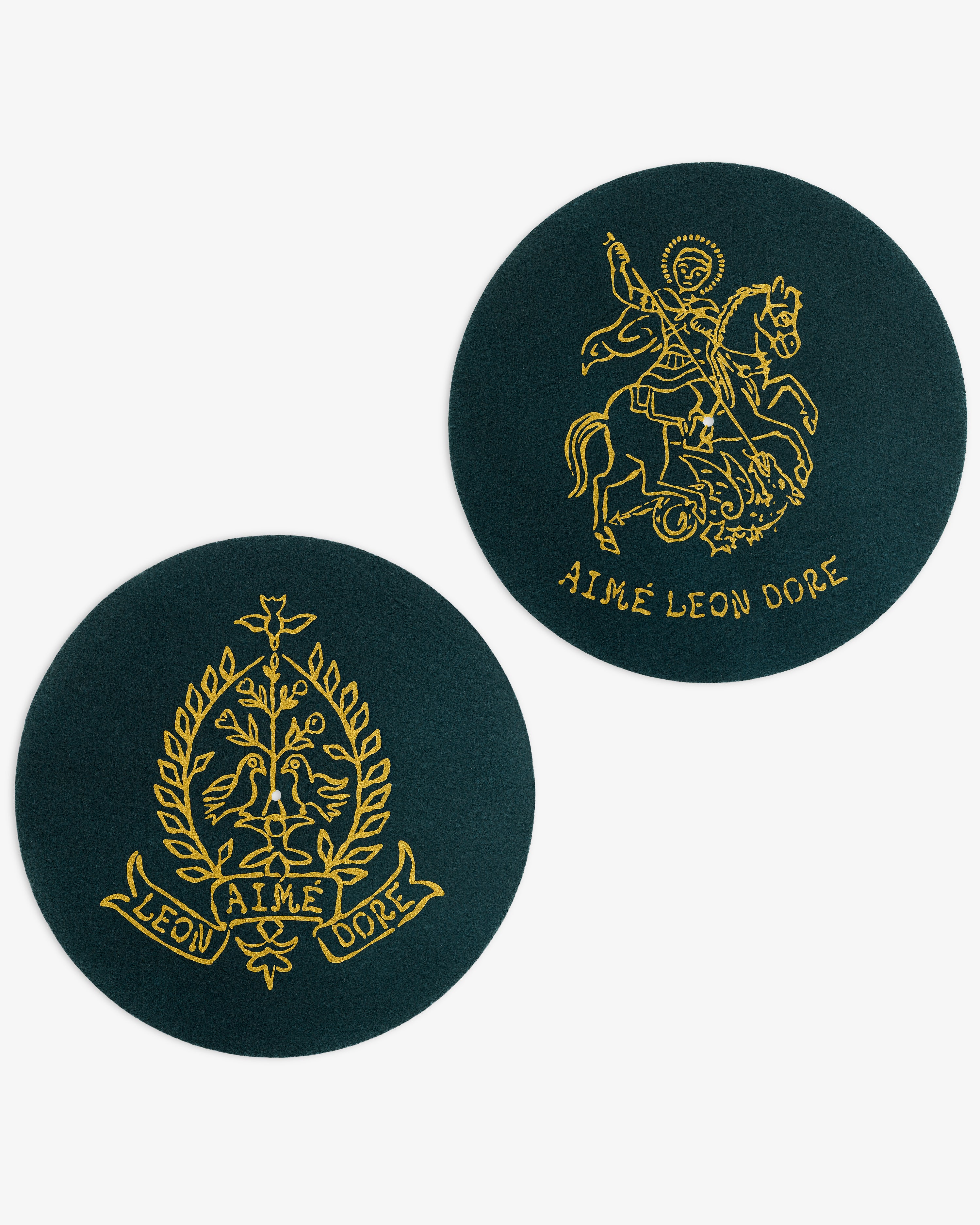 Two dark green Graphic Slip Mats with yellow Aimé Leon Dore crests: one with a wreath, one with a horse rider.