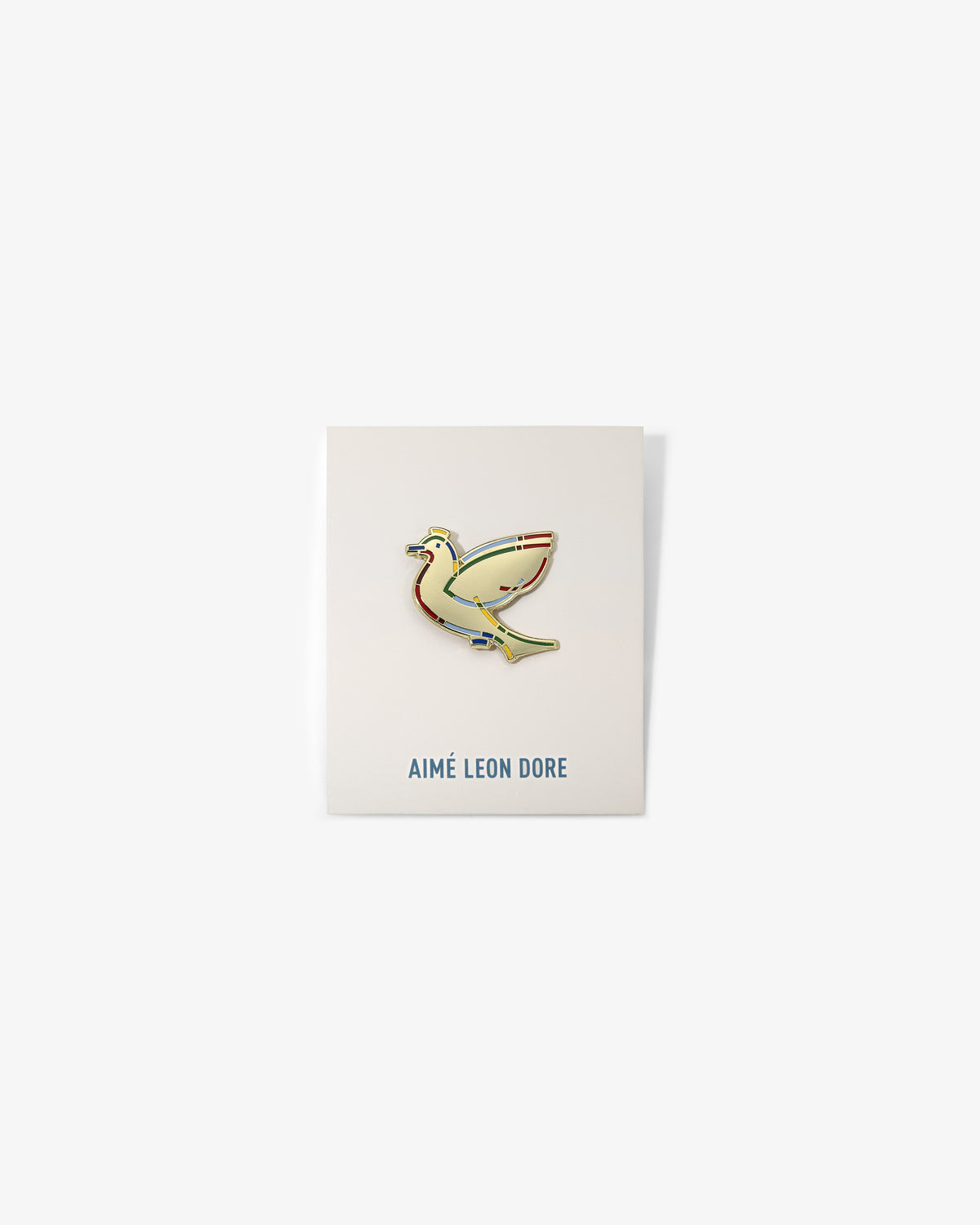 The Graphic Pin, a gold bird-shaped enamel pin, is shown on a white card labeled AIMÉ LEON DORE.
