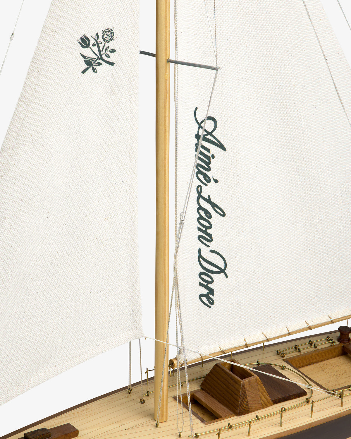 The Walnut Model Sailboat features a rose design and Aimé Leon Dore branding on its white sails.