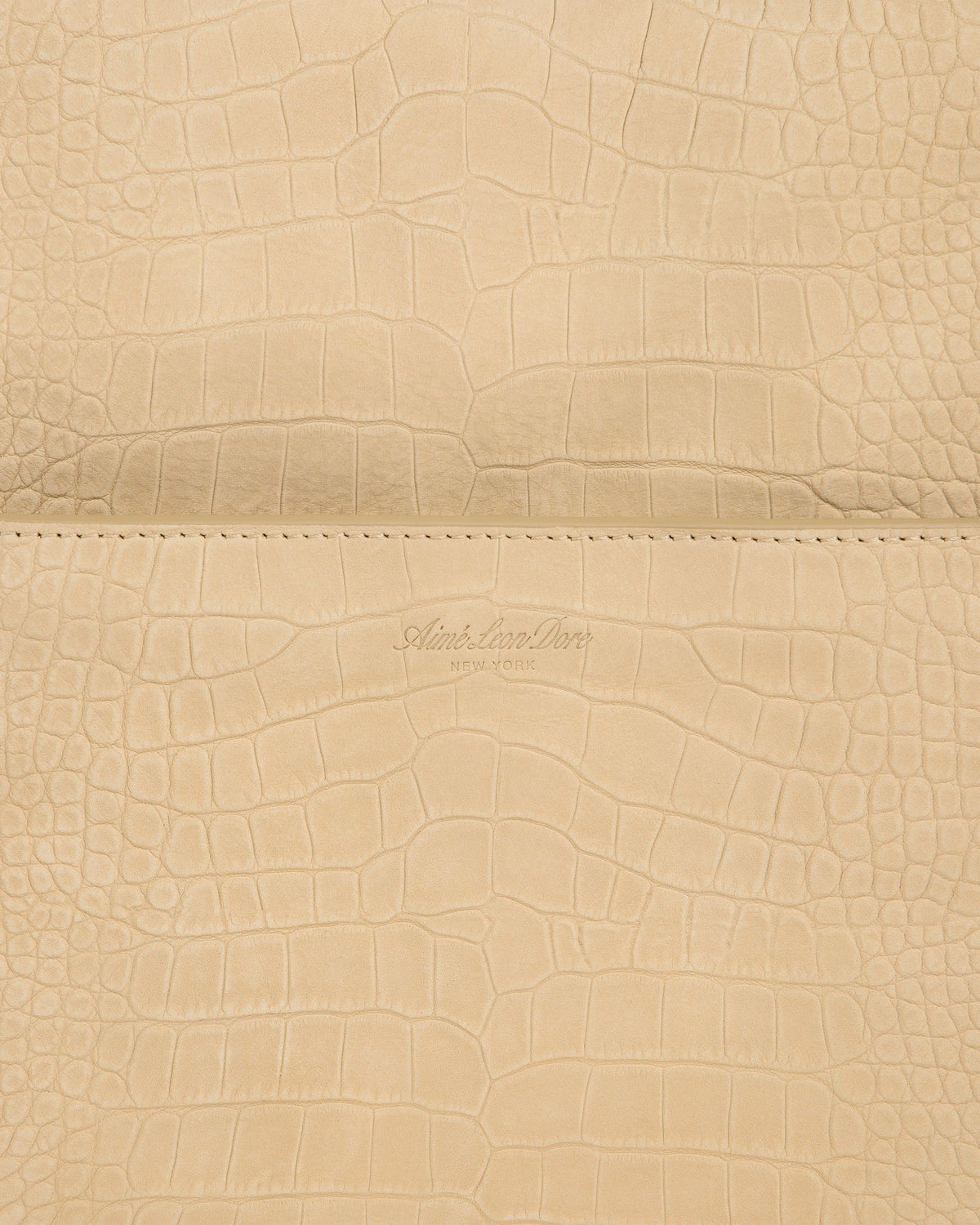 Close-up of beige Croc-Embossed Nubuck Duffle with Aime Leon Dore New York logo debossed at the center.