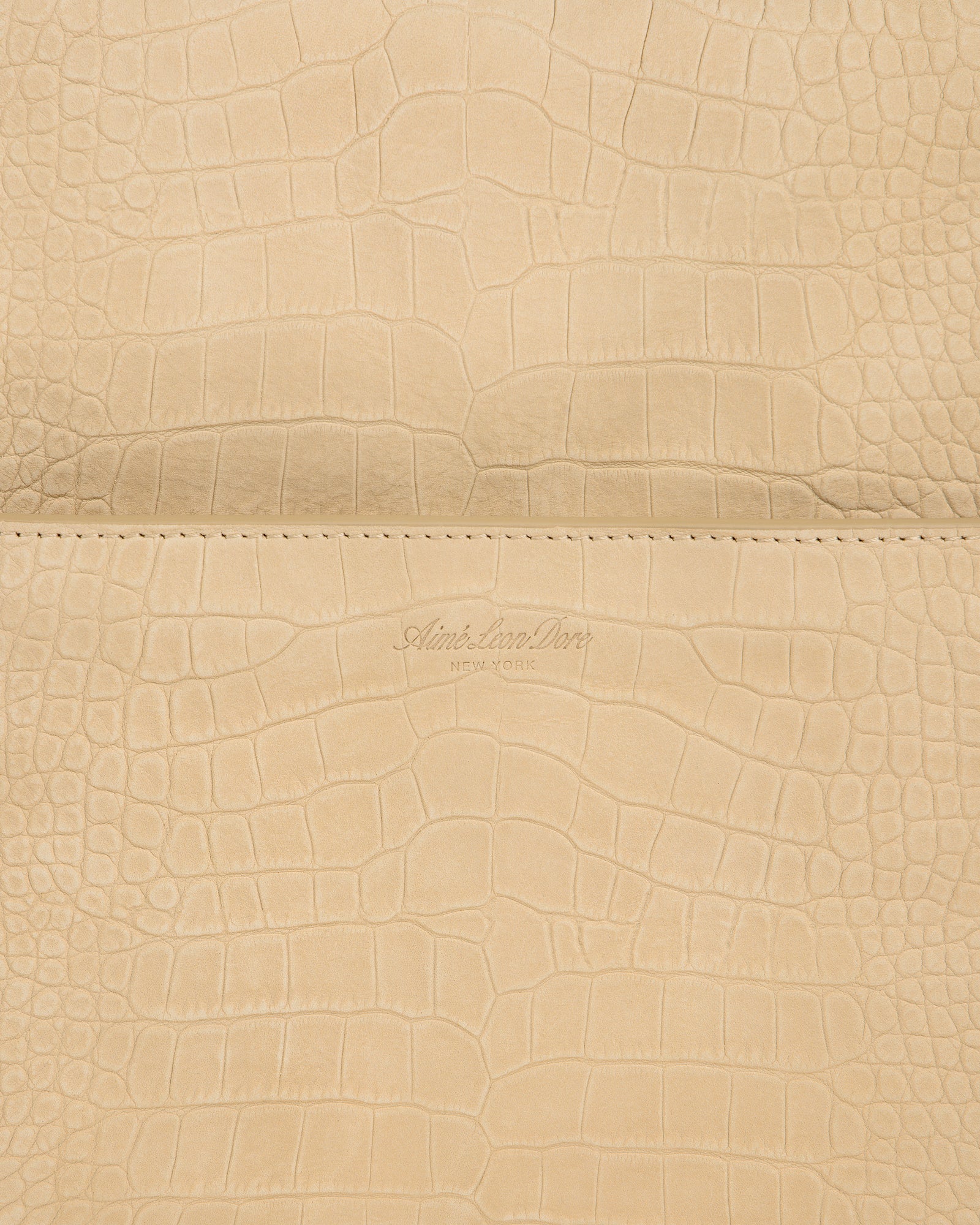 Close-up of beige Croc-Embossed Nubuck Duffle with Aime Leon Dore New York logo debossed at the center.